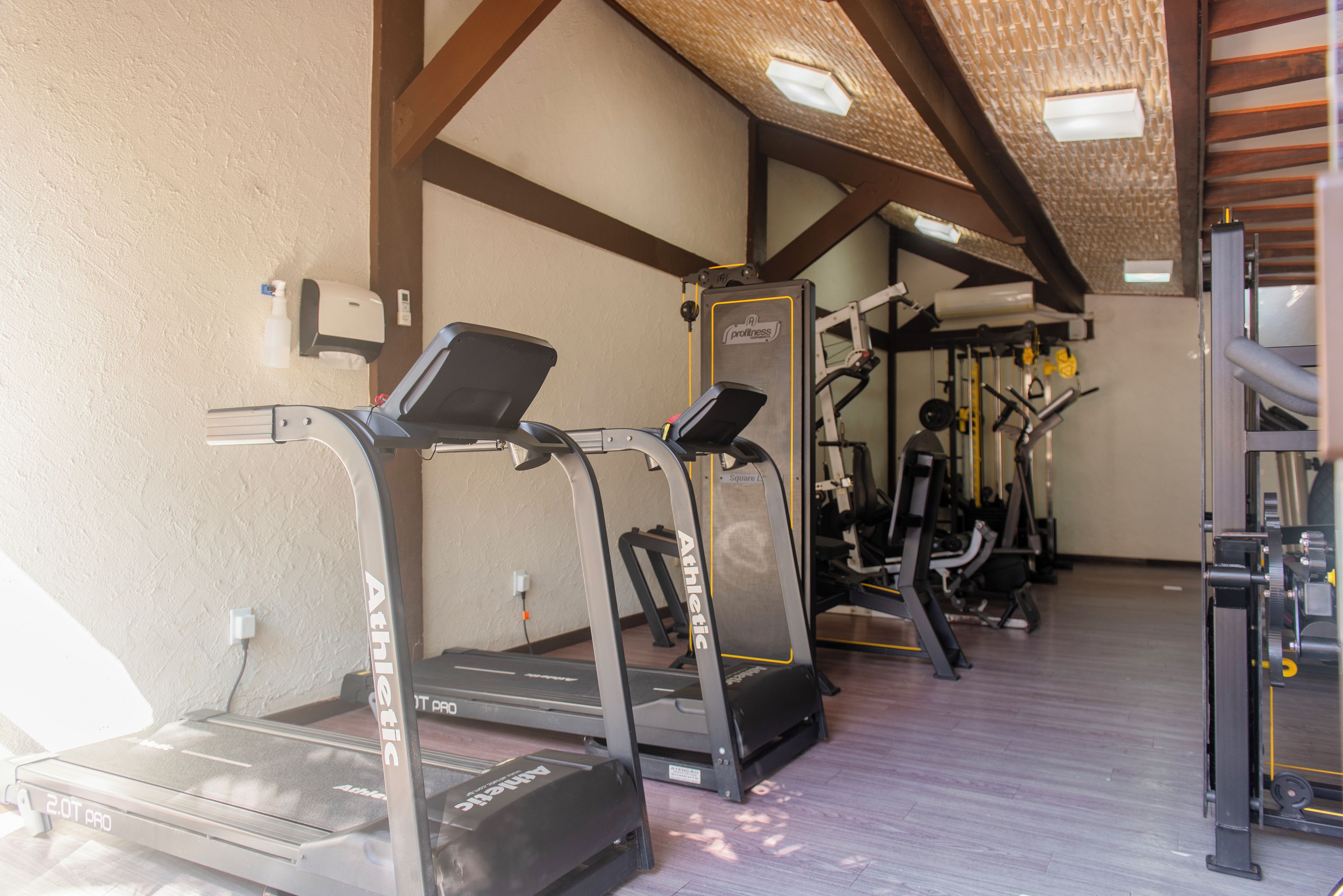 A gym with treadmills, weight machines, and a wall-mounted massage chair.