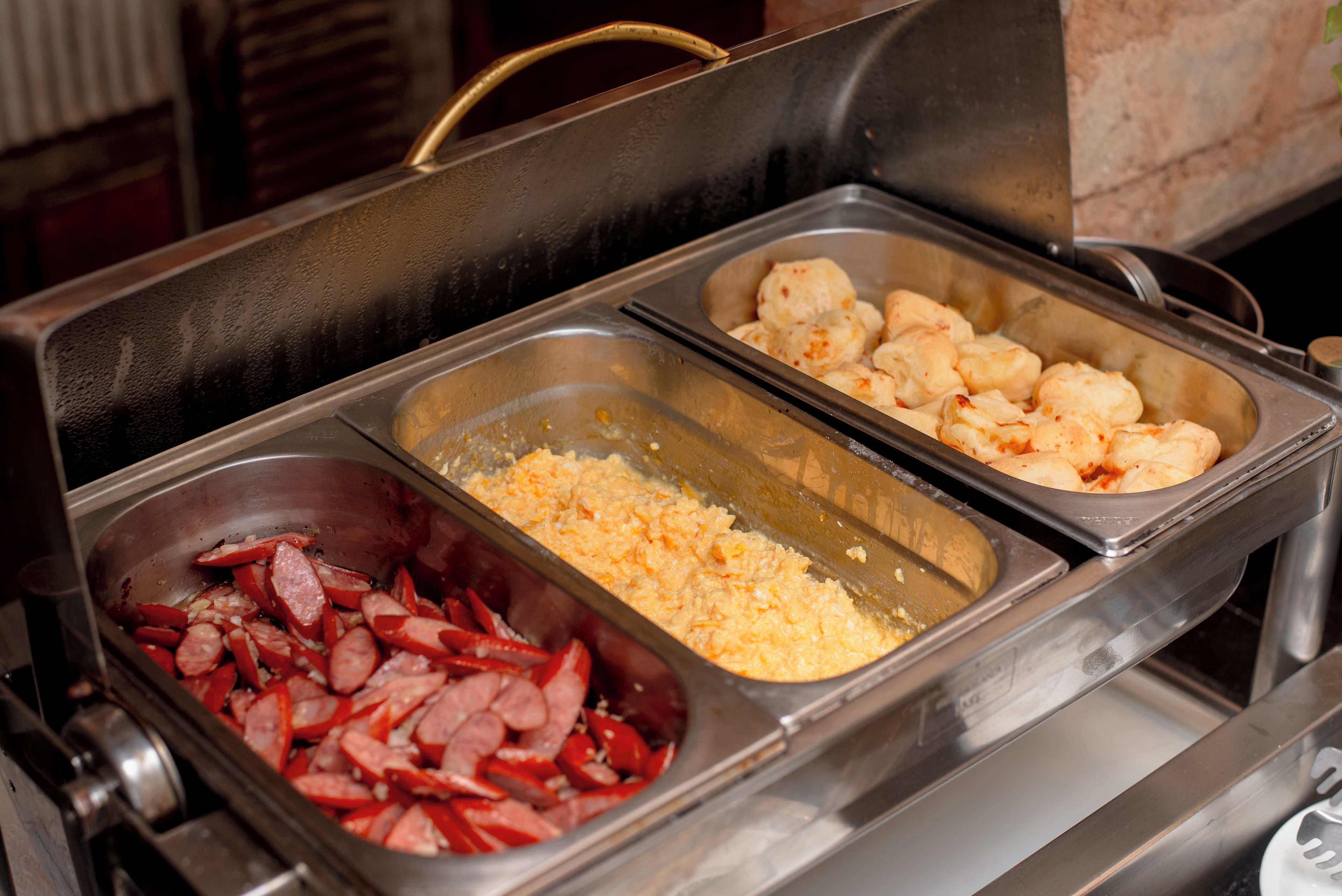 Buffet com diversas opções de comida, incluindo salsichas, queijo e tater tots.