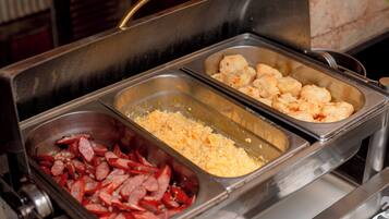 Buffet com diversas opções de comida, incluindo salsichas, queijo e tater tots.