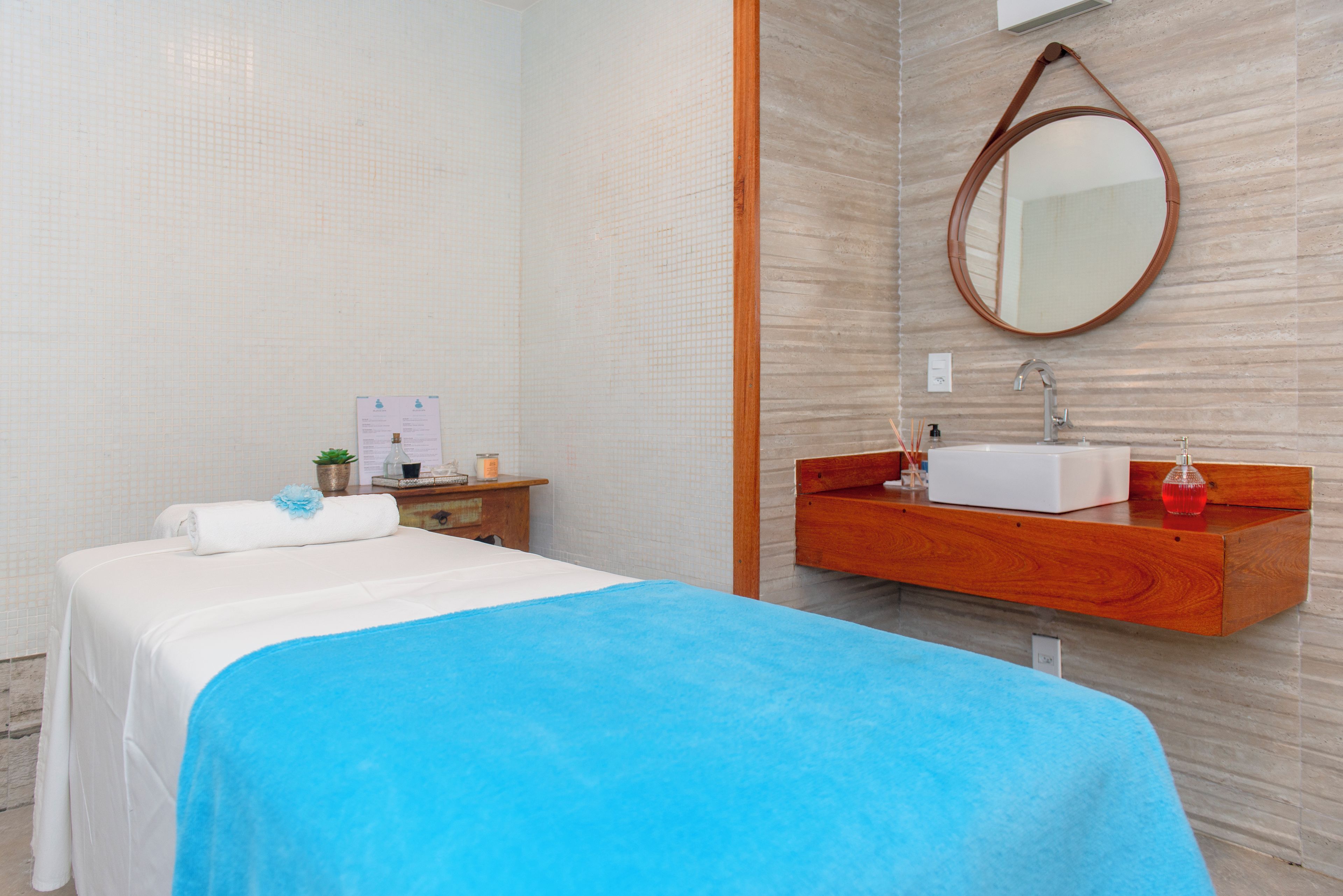 Een hotelkamer met een bed, een houten kaptafel met spiegel en een tafeltje met toiletartikelen.