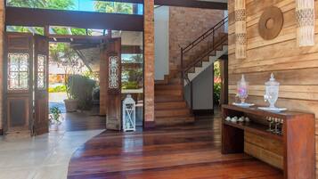 Un ambiente spazioso con una scala in legno, una porta vetrata che dà sull'esterno e una mensola con oggetti decorativi.
