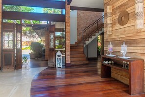 Um interior espaçoso com escada de madeira, porta de vidro para o exterior e prateleira com objetos decorativos.
