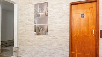 Un pasillo con pared de piedra y puerta de madera con un letrero.
