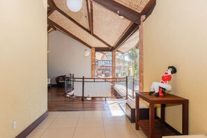 A spacious hallway with a wooden floor, a glass railing, and a view of a traditional building. - Rio Buzios Boutique Hotel (Búzios)