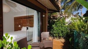 A hotel room with a bed, a chair, and a view of the garden. - Rio Buzios Boutique Hotel (Búzios)