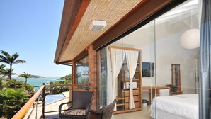 A balcony with wicker furniture, a bed, and a desk. - Rio Buzios Boutique Hotel (Búzios)