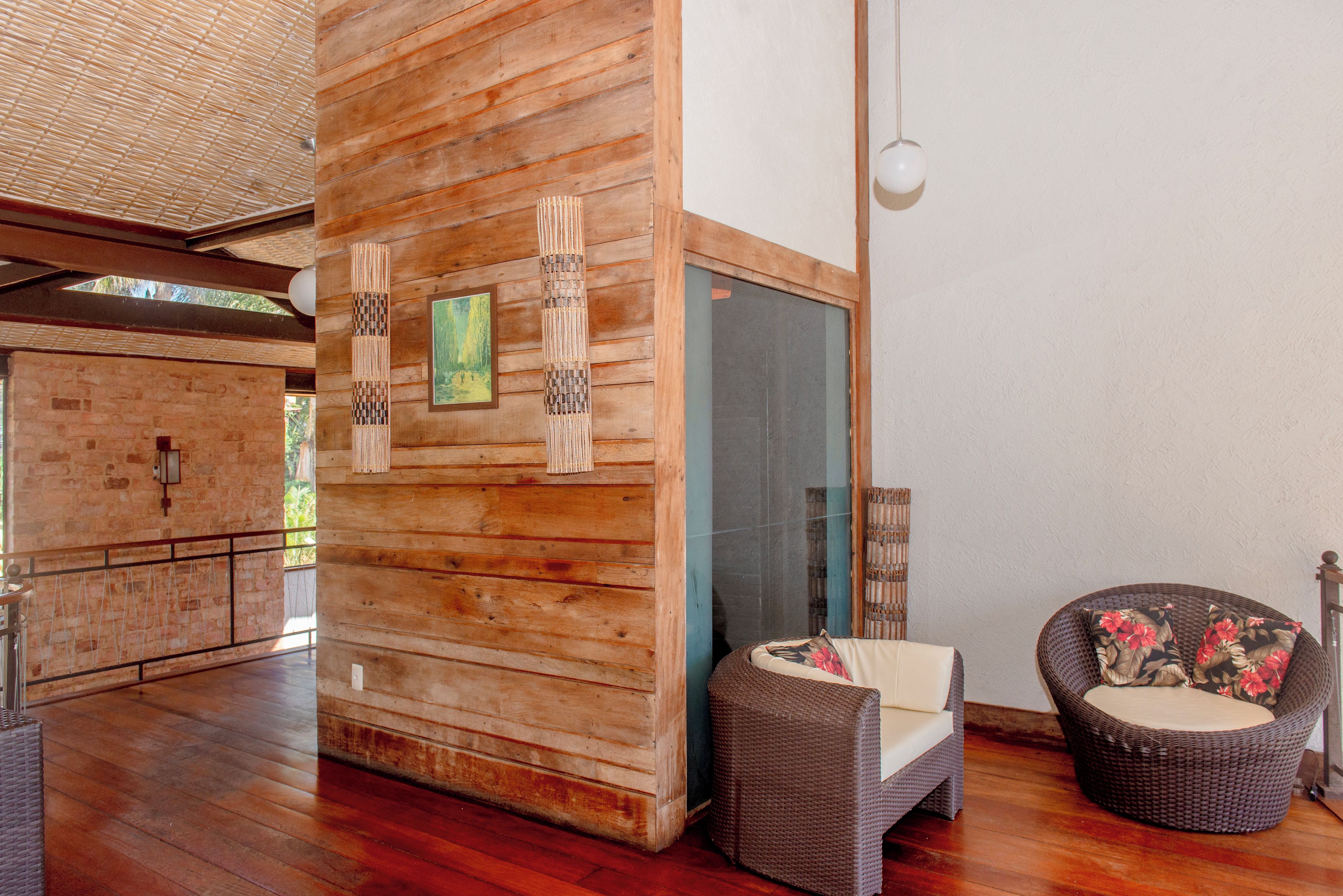 A wooden interior with a glass door, wicker furniture, and a stone wall.