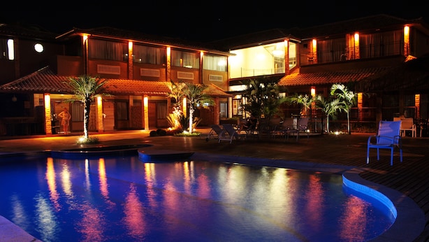 A hotel with a swimming pool, outdoor seating, and a well-lit facade. - Rio Buzios Boutique Hotel (Búzios)