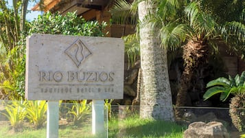 A sign for 'RIO BUZIOS BOUTIQUE HOTEL & SPA' with a tropical backdrop.