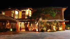 A large, two-story building with a traditional architectural style, featuring a prominent entrance with glass doors and a tiled roof. - Rio Buzios Boutique Hotel (Búzios)