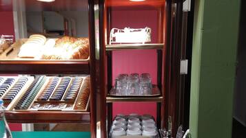 Una vitrina de panadería con pan, pasteles, y una variedad de vasos y utensilios.