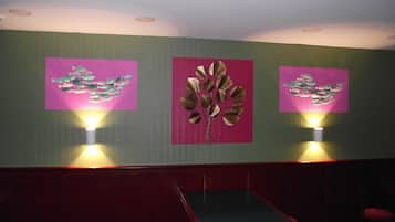 A room with a green wall, two wall-mounted lights, and three framed artworks depicting fish.