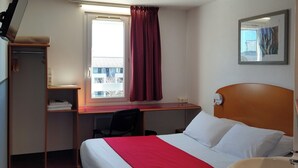 A hotel room with a bed, a desk, a chair, a television, a window with curtains, a bathroom with a sink, and a framed picture on the wall. - Quick Palace Le Mans Nord St Saturnin (Saint-Saturnin)