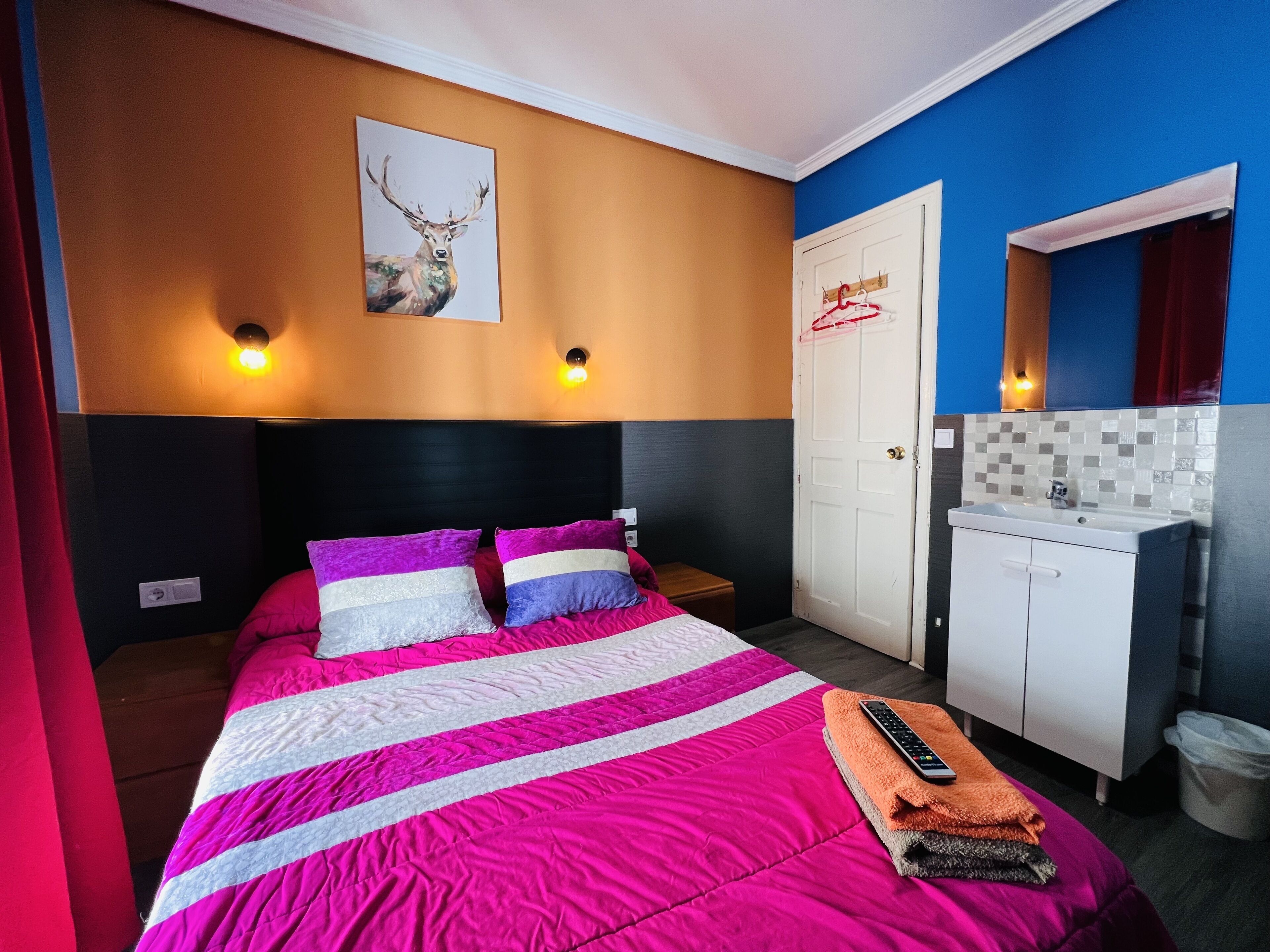 Une chambre d’hôtel comprenant un lit, une table de chevet, une armoire, une salle de bain et un tableau au mur.