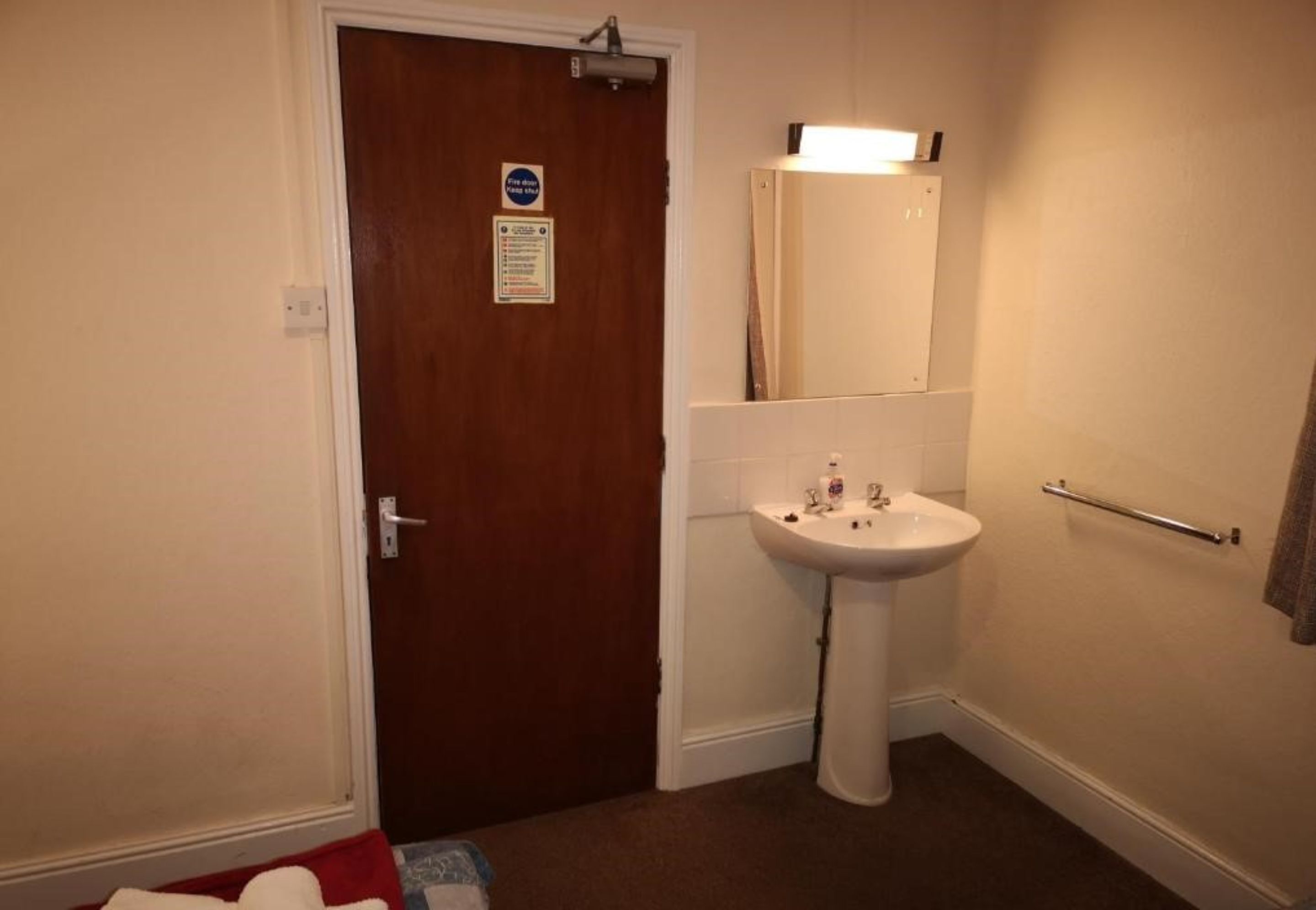 A bathroom with a white sink, a mirror, and a towel rack.