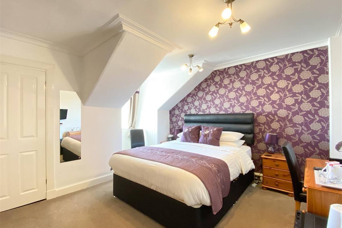 A bedroom with a large bed, a desk, and a chair.