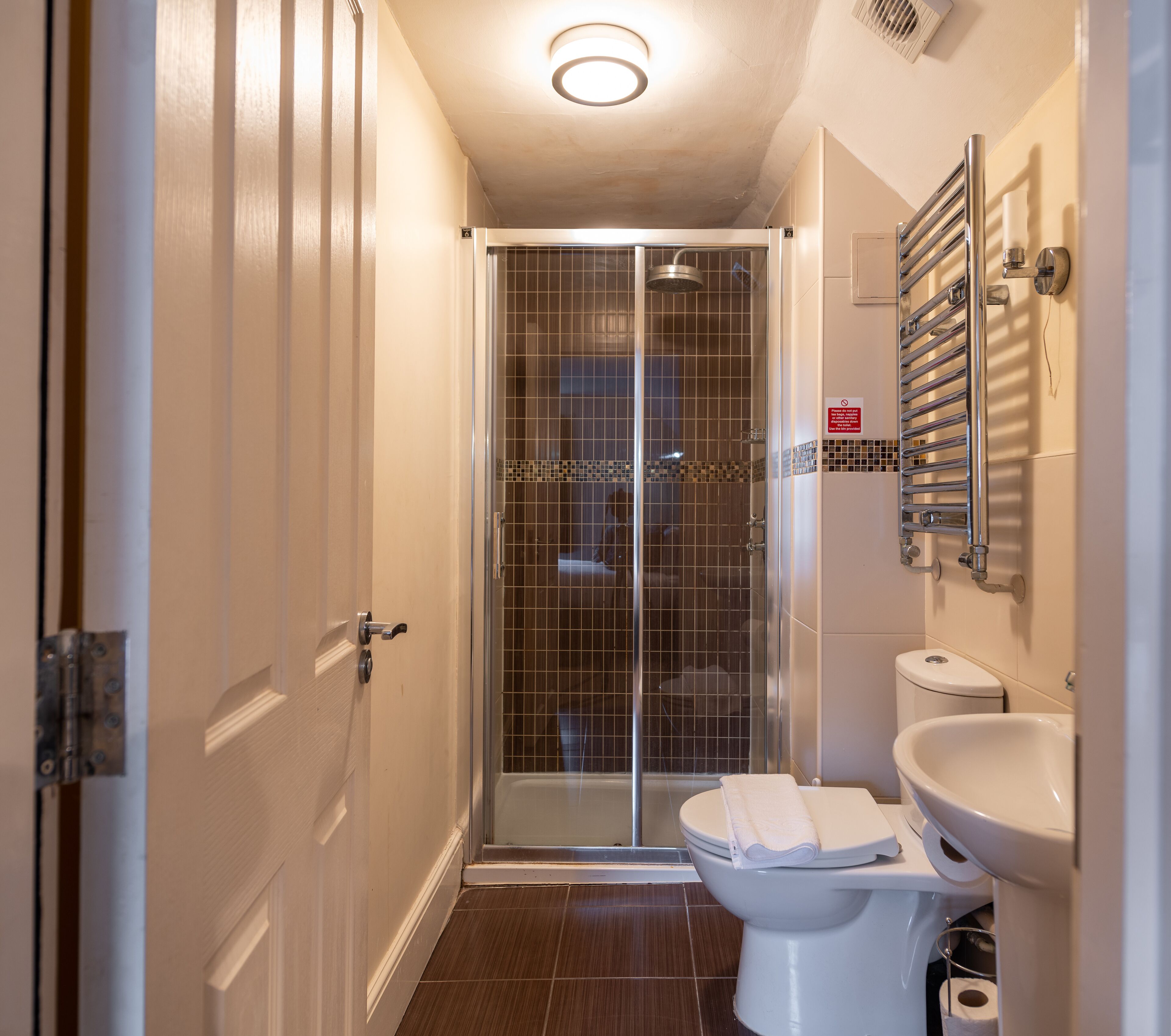 Un baño con cabina de ducha de vidrio, inodoro y lavabo.