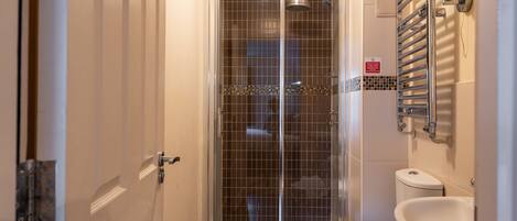 Un baño con cabina de ducha de vidrio, inodoro y lavabo.
