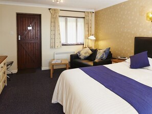 A hotel room with a bed, a nightstand, a lamp, a dresser, and a door. - The Marsham Arms Inn (Norwich)