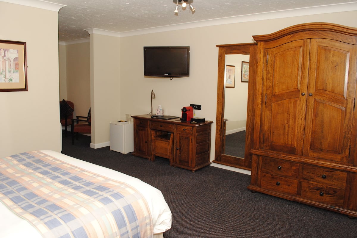 Una habitación de hotel con cama, escritorio, televisión y armario.