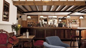 A bar area with wooden beams, bar stools, and a counter with bottles and glasses. - The Marsham Arms Inn (Norwich)