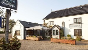 A building with a covered outdoor seating area, a sign for 'Marsham Arms Freehouse Inn', and a gravel driveway. - The Marsham Arms Inn (Norwich)