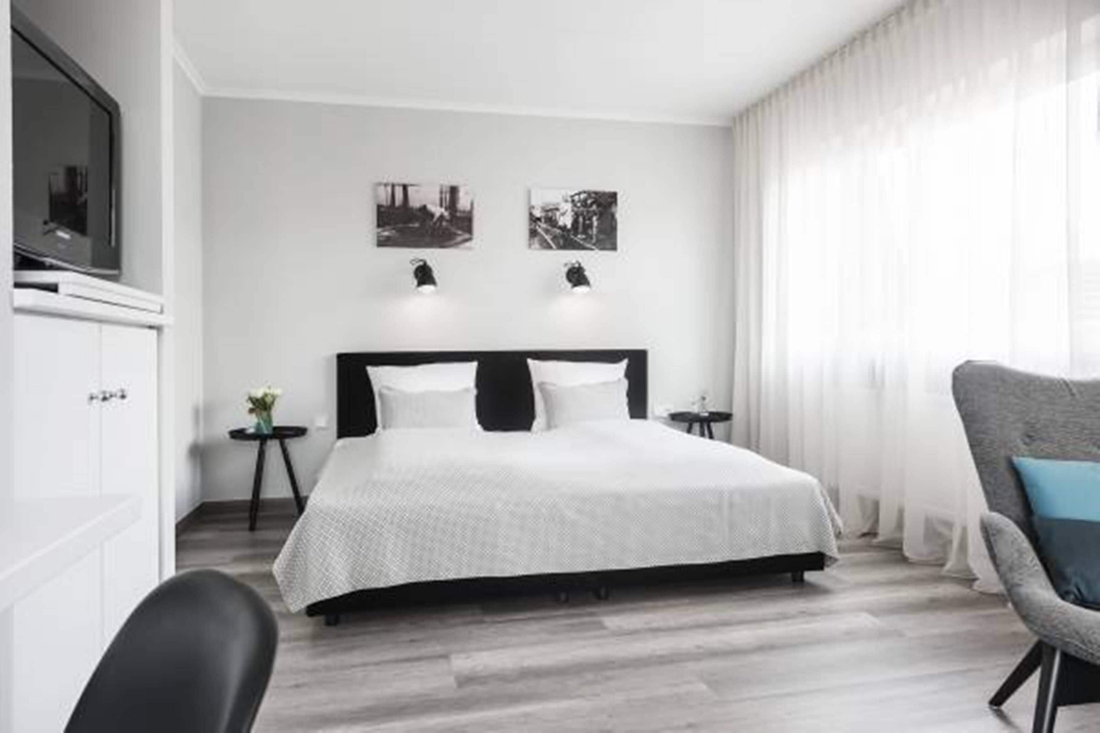 Une chambre d’hôtel moderne avec un grand lit, un téléviseur à écran plat, une petite table d’appoint et une chaise.