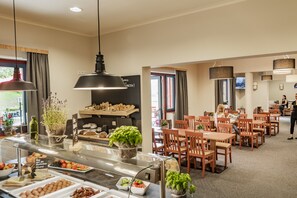 Un restaurante con mostrador de buffet, mesas y sillas de madera.