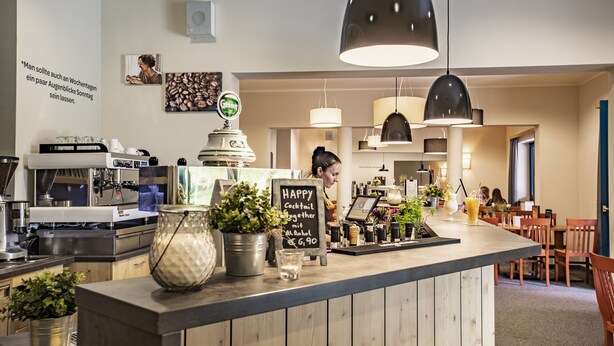 A bar area with a counter, coffee machines, and a chalkboard menu. - JUFA Hotel Maria Lankowitz am See (Maria Lankowitz)