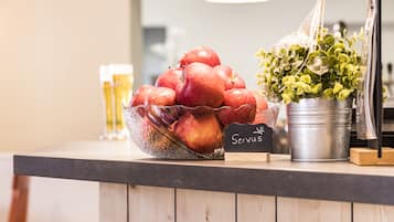 A wooden counter with a bowl of red apples, a potted plant, and a sign that reads "Servus".