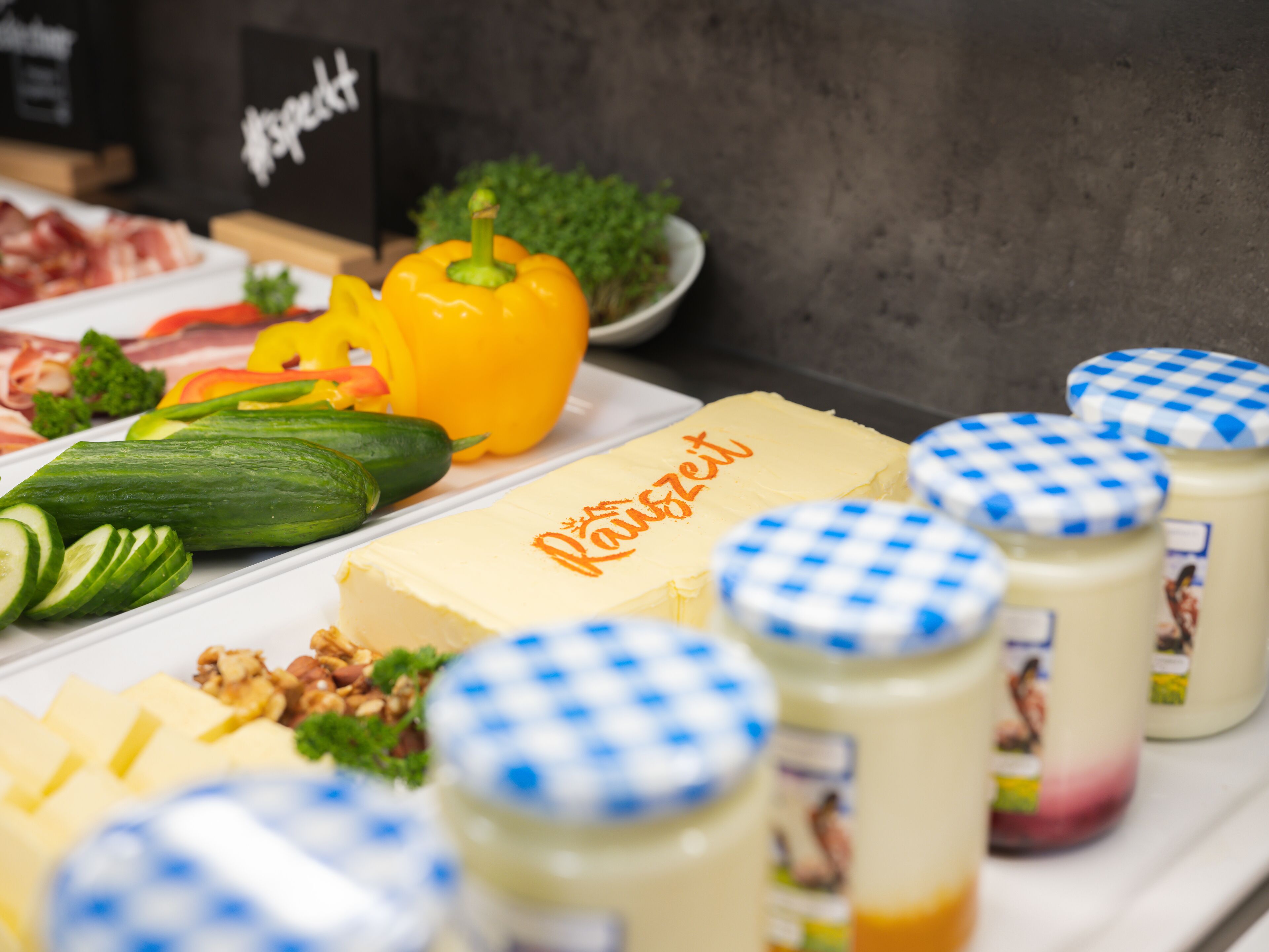 Una mesa de buffet con diversos alimentos, incluyendo queso, verduras y salsas.