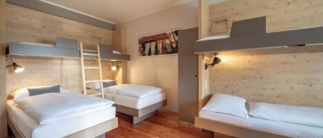 Ein Zimmer mit Etagenbetten, Holzboden und Wandlampen.