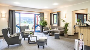 A modern hotel room with a sofa, armchairs, a coffee table, and a view of the outdoors. - JUFA Hotel Maria Lankowitz am See (Maria Lankowitz)