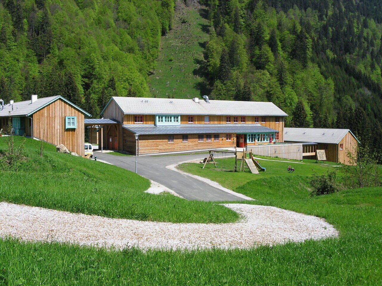 A lodge with a long building and a smaller structure, surrounded by green hills.