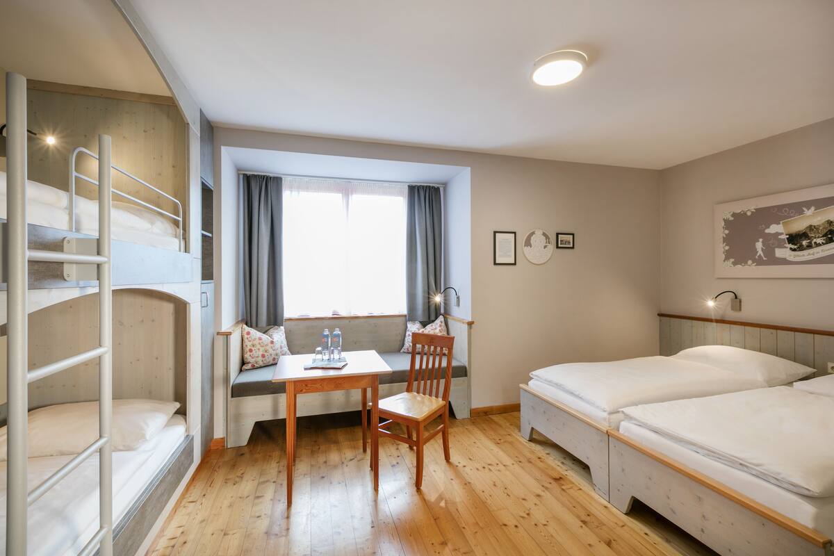 Een kamer met stapelbedden, een bureau en een raam met gordijnen.