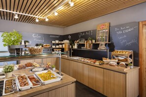 Zona de bufé con diferentes opciones de comida y un menú en la pizarra.