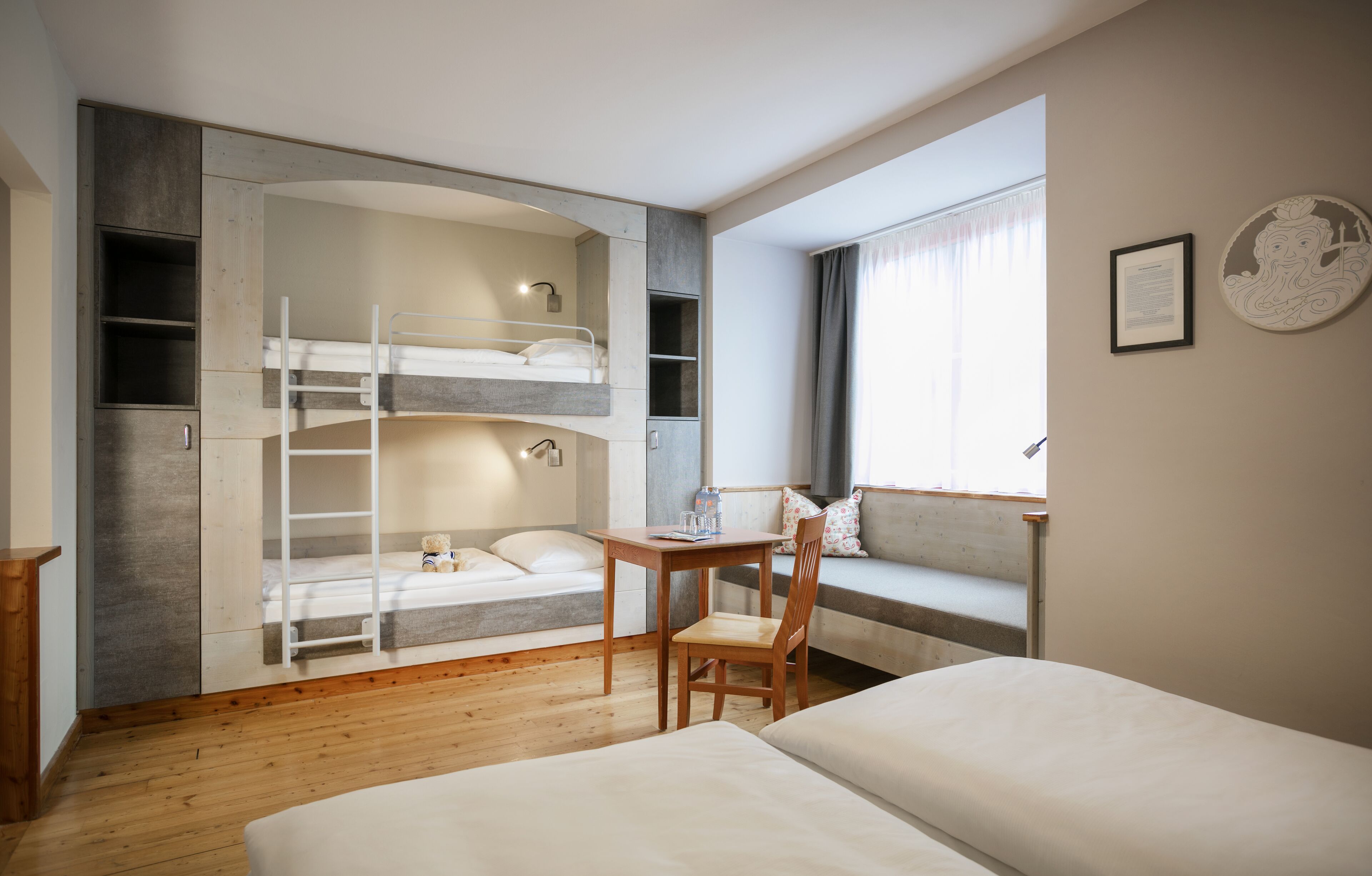 A bedroom with a bunk bed, a desk, and a window with curtains.
