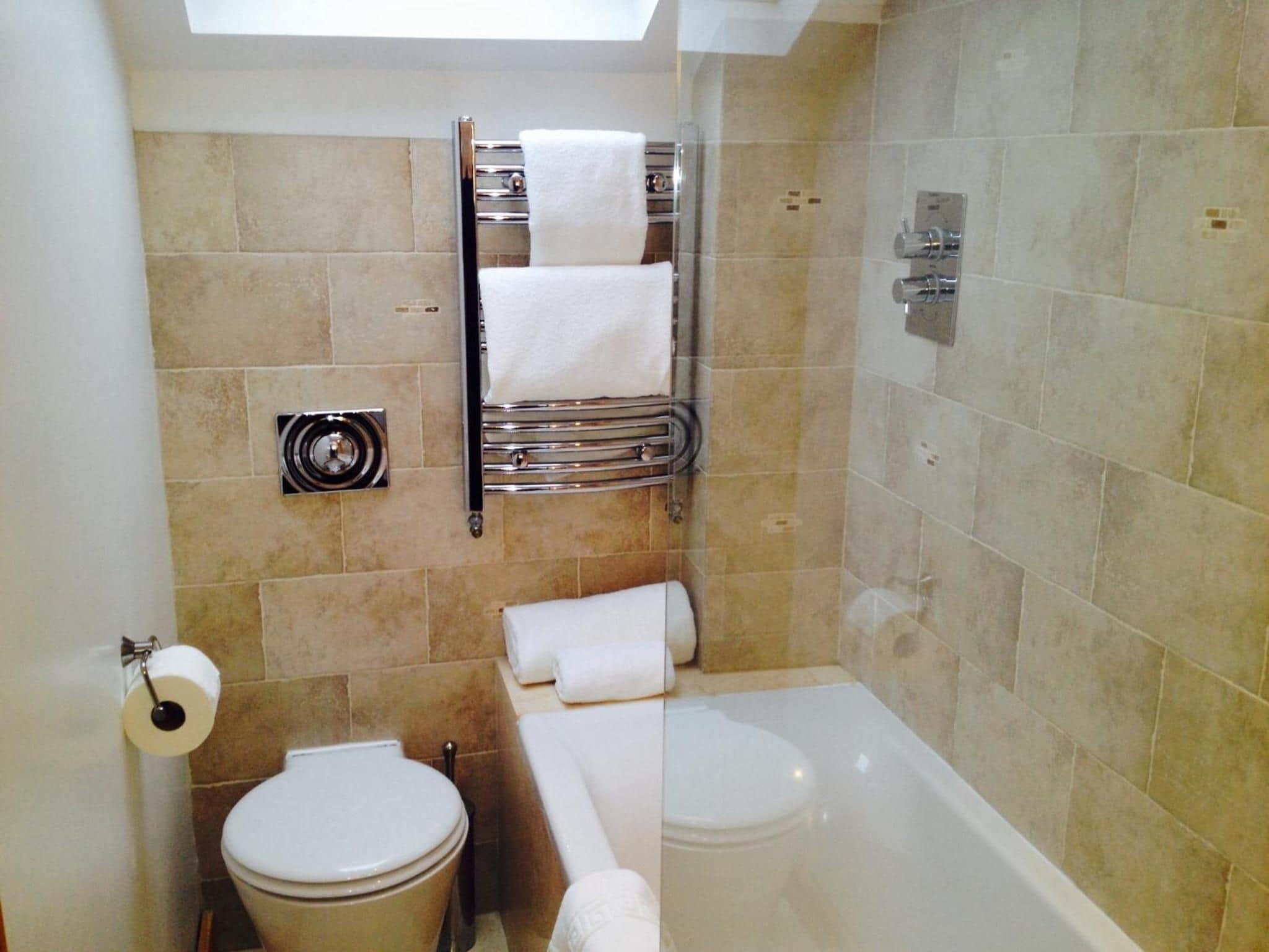 A bathroom with a toilet, a towel rack, and a bathtub.