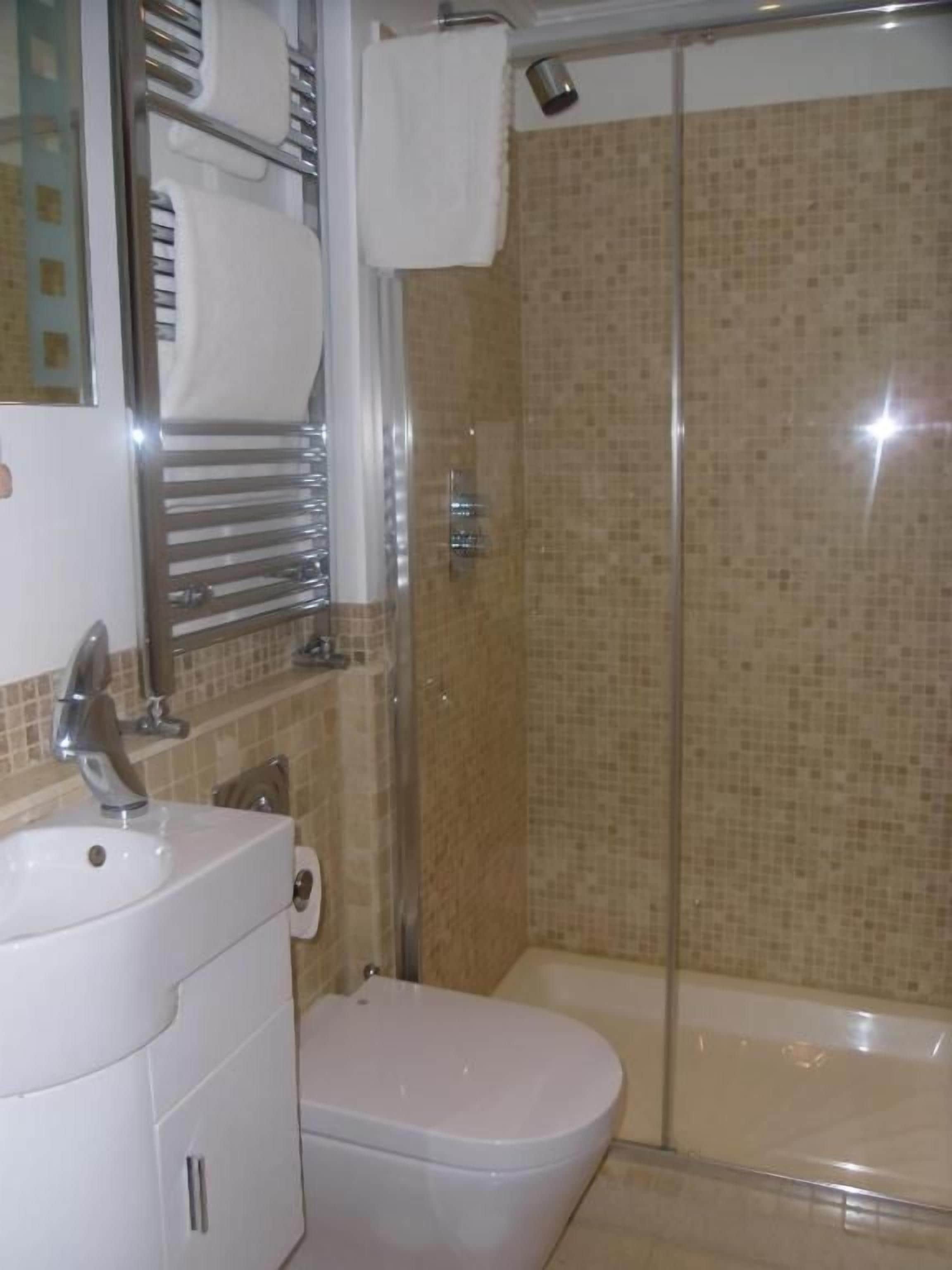 Un baño con inodoro, lavamanos y zona de ducha.