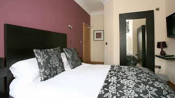 A hotel room with a large bed, a dark headboard, a television, and a mirror.