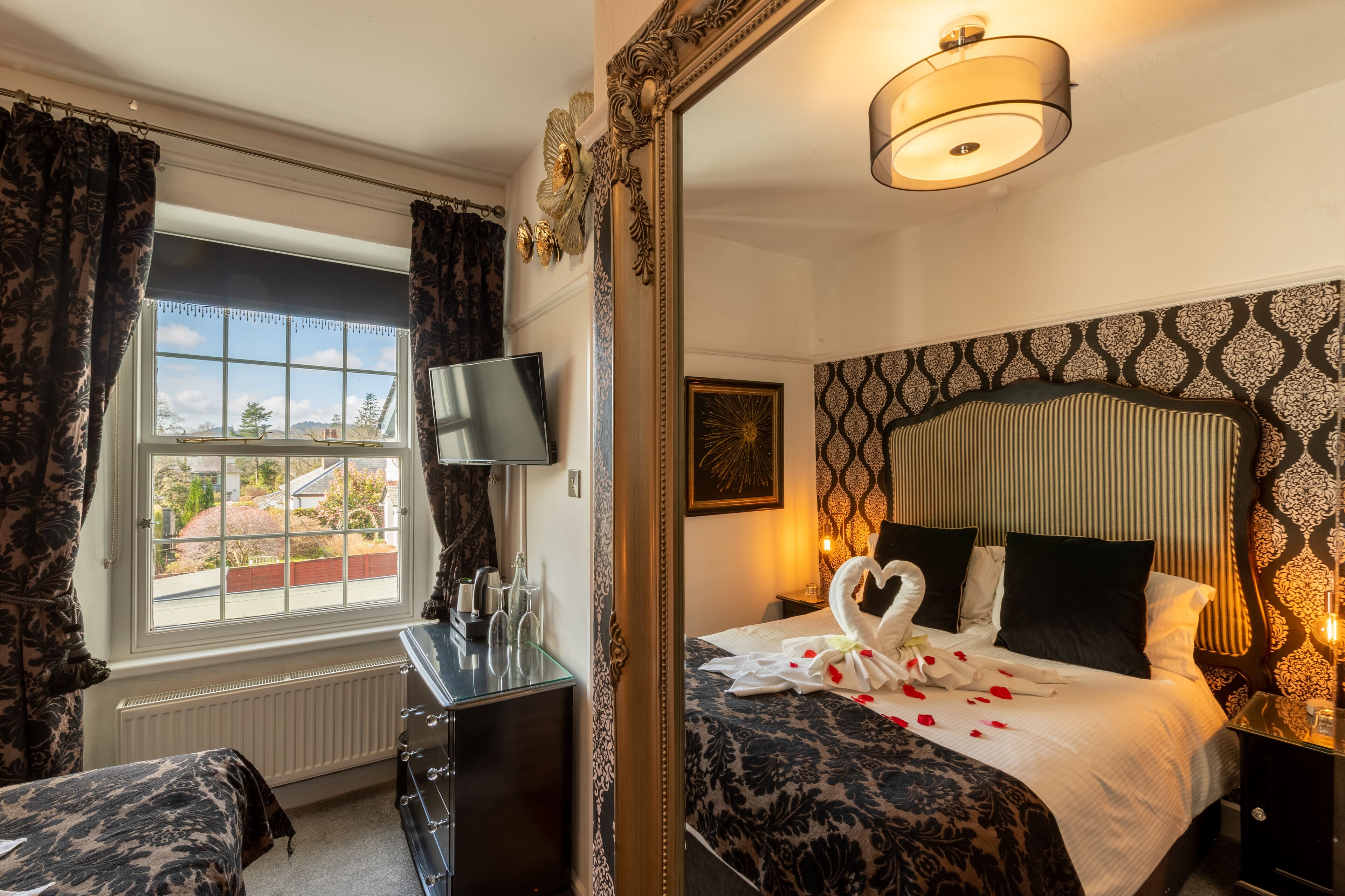 Een hotelkamer met een groot bed, een dressoir, een televisie en een raam met gordijnen.