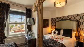 Een hotelkamer met een groot bed, een dressoir, een televisie en een raam met gordijnen.