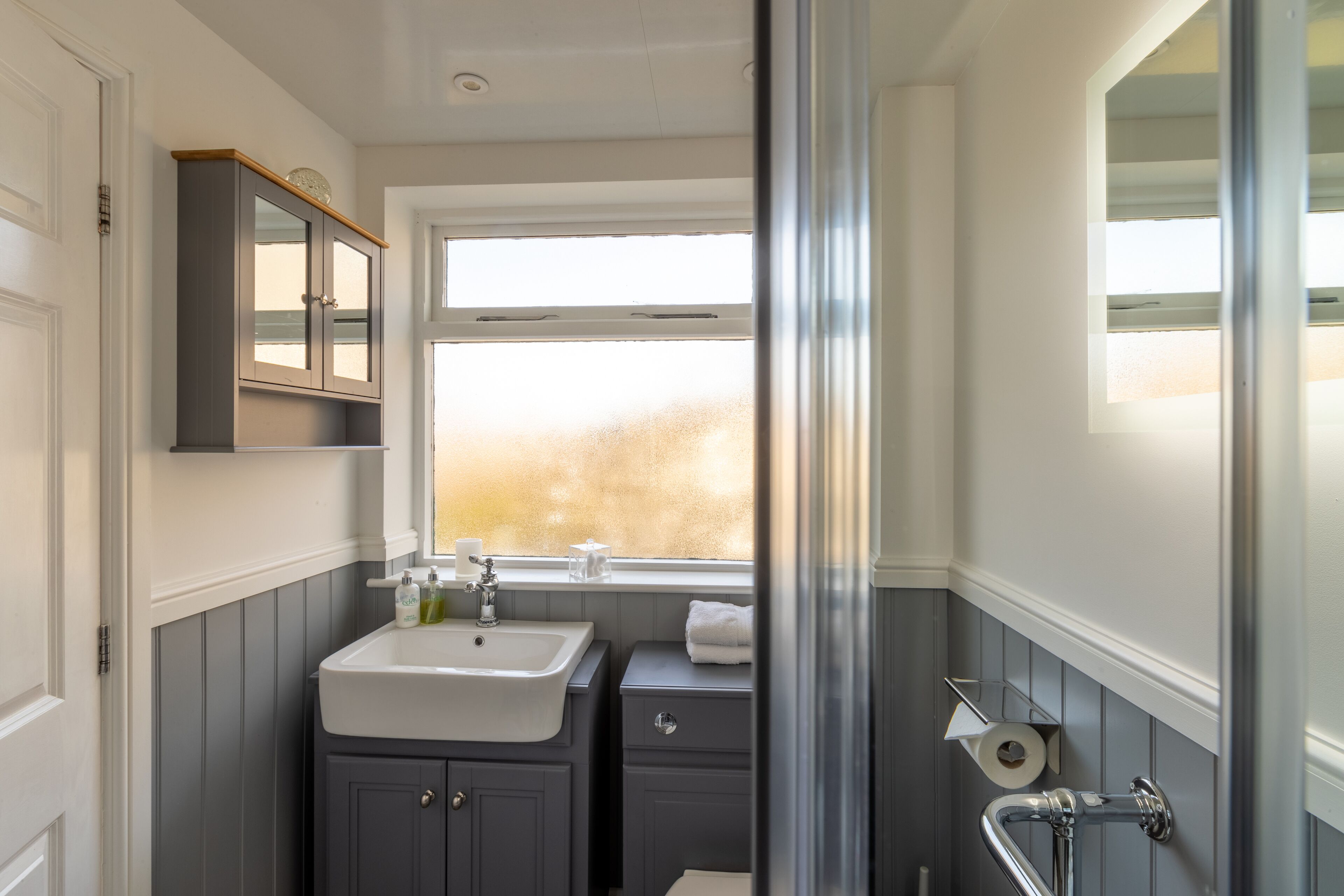 Une salle de bain avec un lavabo, un miroir et une fenêtre.