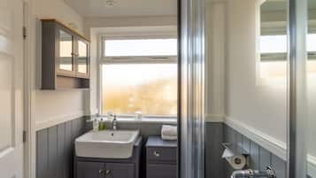 Une salle de bain avec un lavabo, un miroir et une fenêtre.