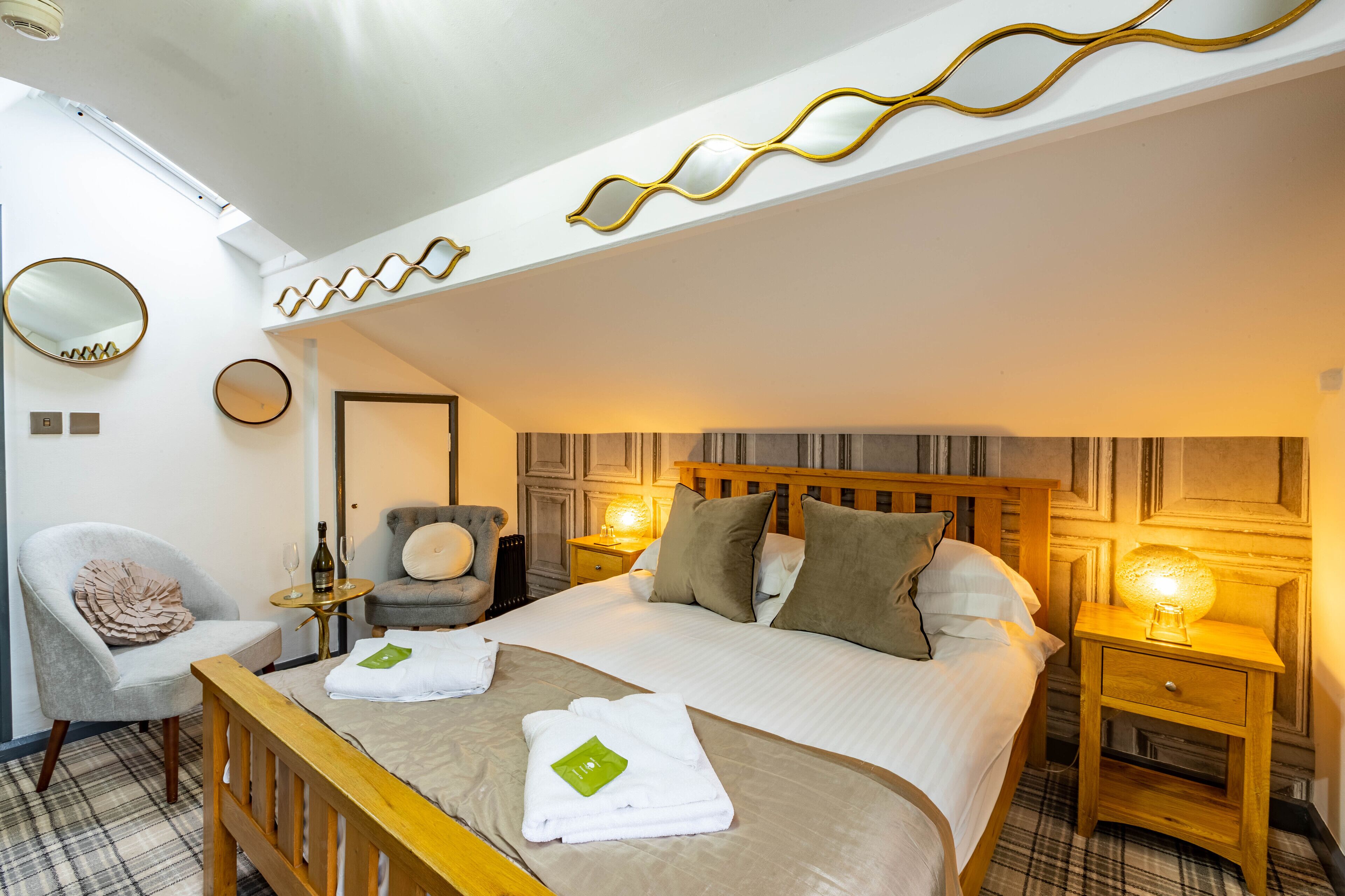 A hotel room with a bed, a chair, a nightstand, and a mirror.