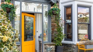 A modern building with a bright yellow door, stone walls, and a number '6' sign. - Holly Lodge Guest House (Windermere)