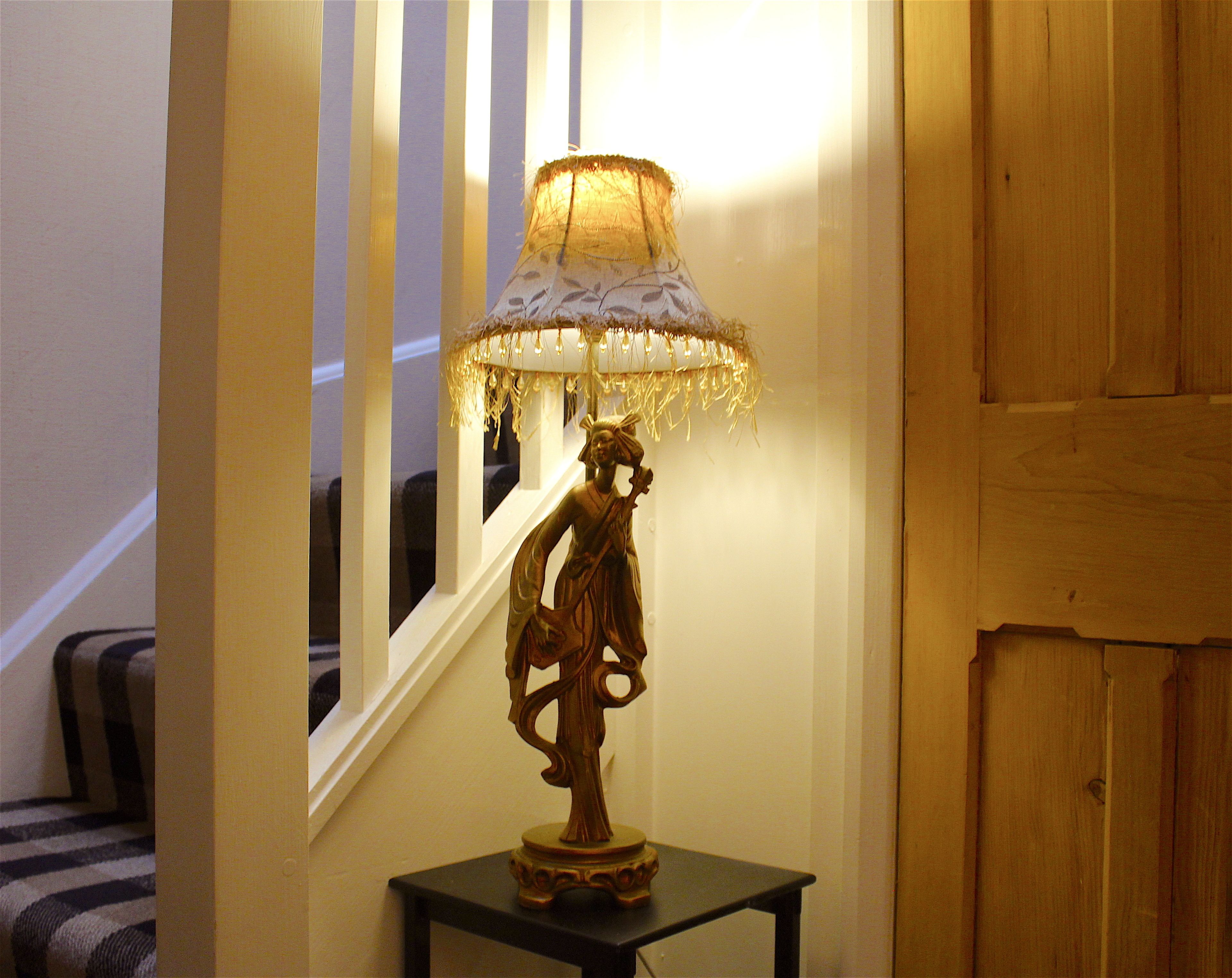 A lamp with a decorative shade on a small table in a hallway.