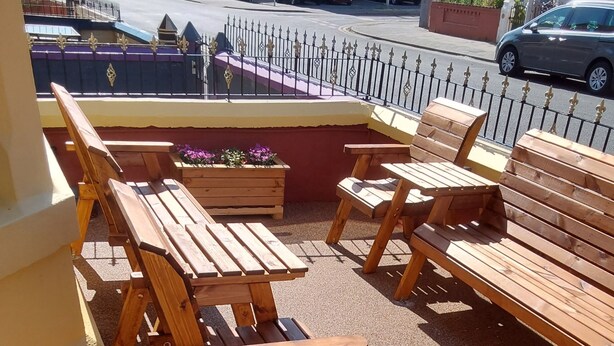 A balcony with wooden furniture and a view of the street. - Bianca Guesthouse (Blackpool)