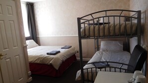 A hotel room with two beds, one with a bunk bed and the other with a single bed. There is a desk with a chair and a coffee maker. - Bianca Guesthouse (Blackpool)
