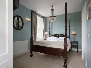 A four-poster bed with a wooden frame and a chandelier above.